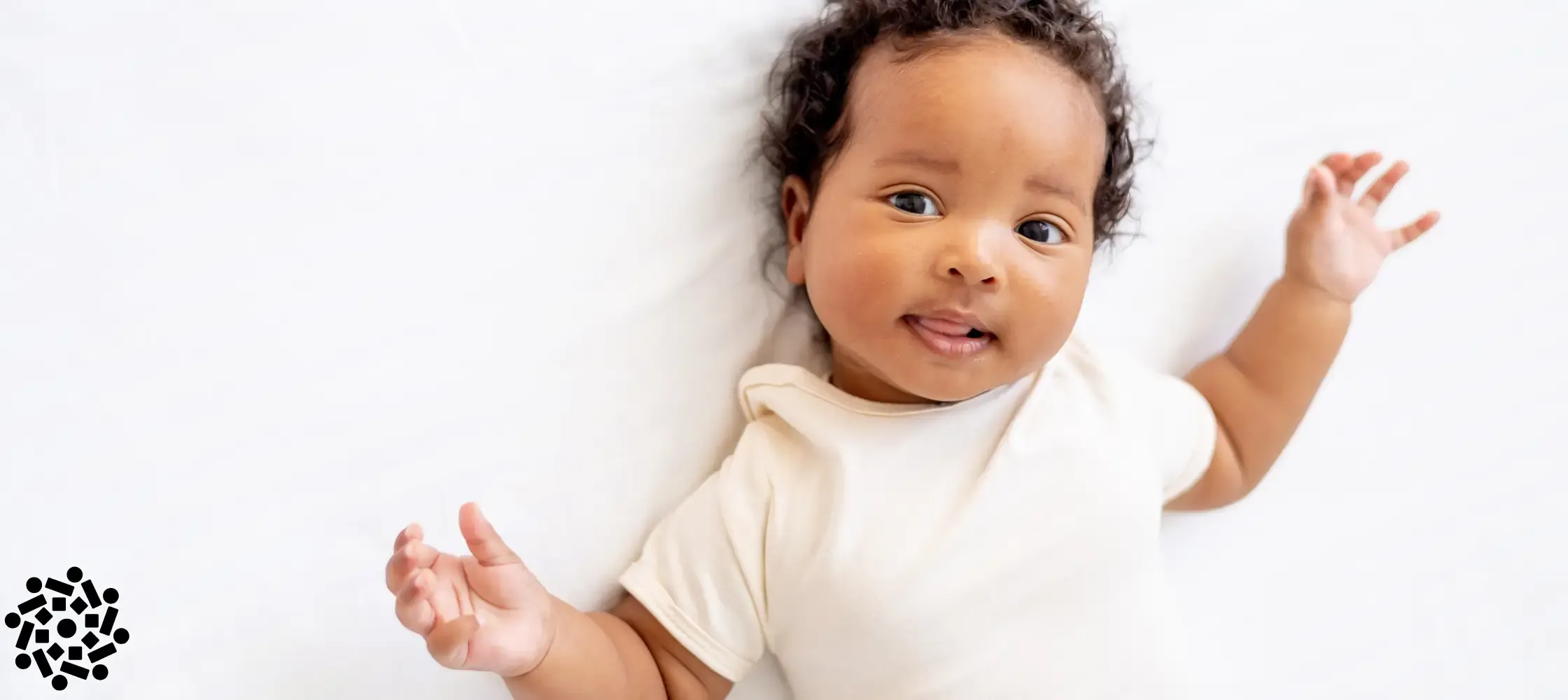 Bebê sorridente deitado na cama. Mortalidade infantil caiu drasticamente desde os anos 1990.
